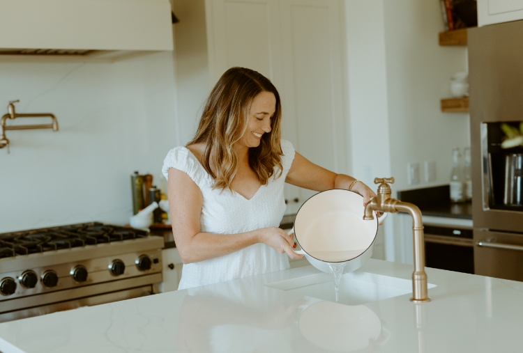 woman drains pot in kitchen sink