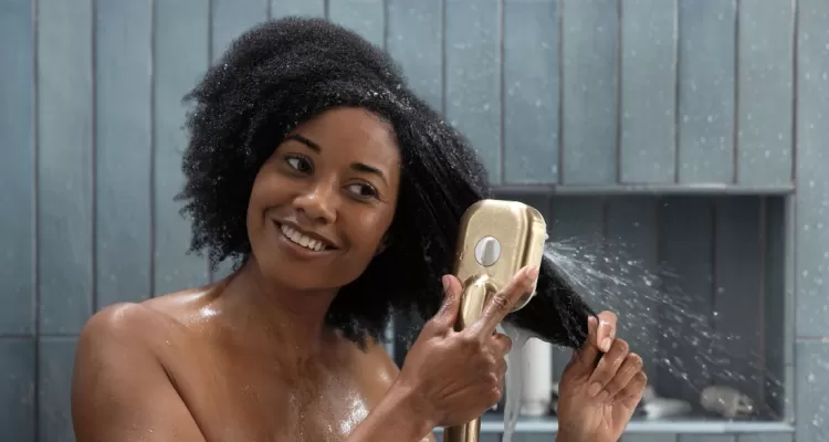 Woman with curly hair detangling her hair in the shower